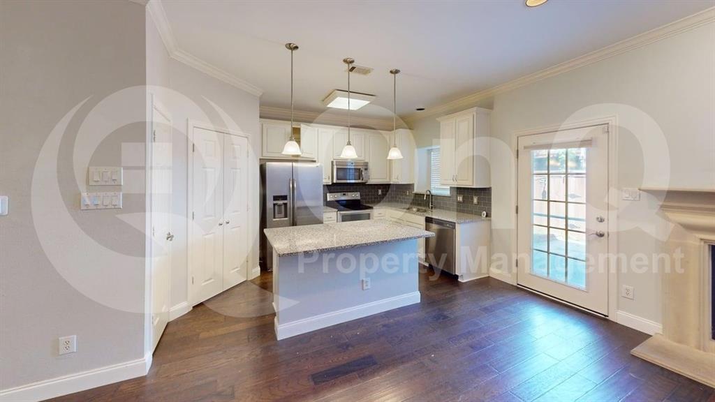 18240 Midway Road, Unit 1204 Dallas, TX 75287 - Photo 3 of 27 Kitchen featuring a central island with a light-toned countertop, stainless steel appliances, white cabinetry, and wood-finish flooring