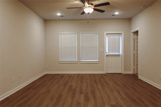 an empty room with wooden floor and windows