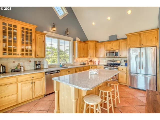 a large kitchen with kitchen island a large window cabinets and stainless steel appliances