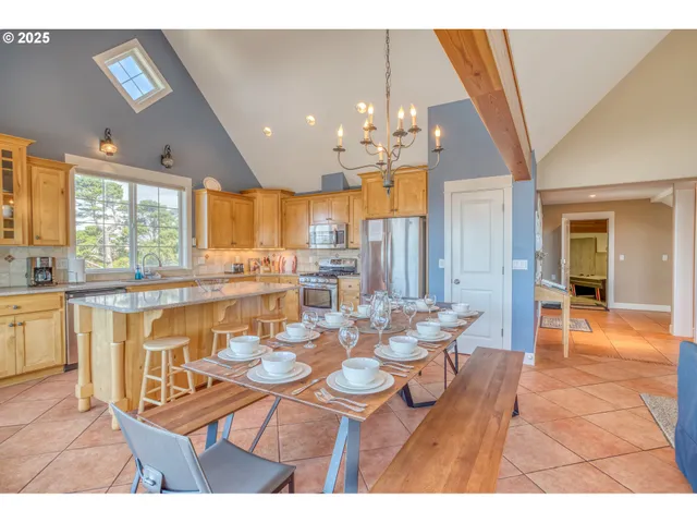 a dining room with furniture a chandelier a large window and kitchen view