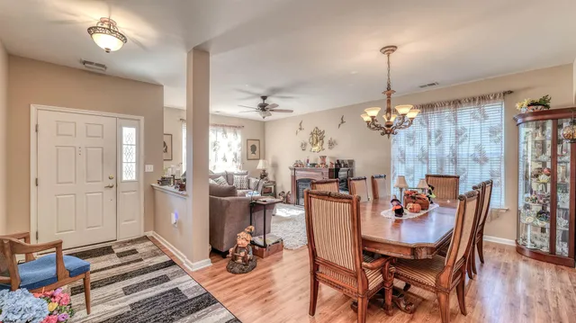 a view of a dining room and livingroom with furniture wooden floor a chandelier