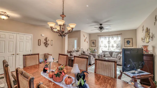 a view of a dining room with furniture a chandelier and a window