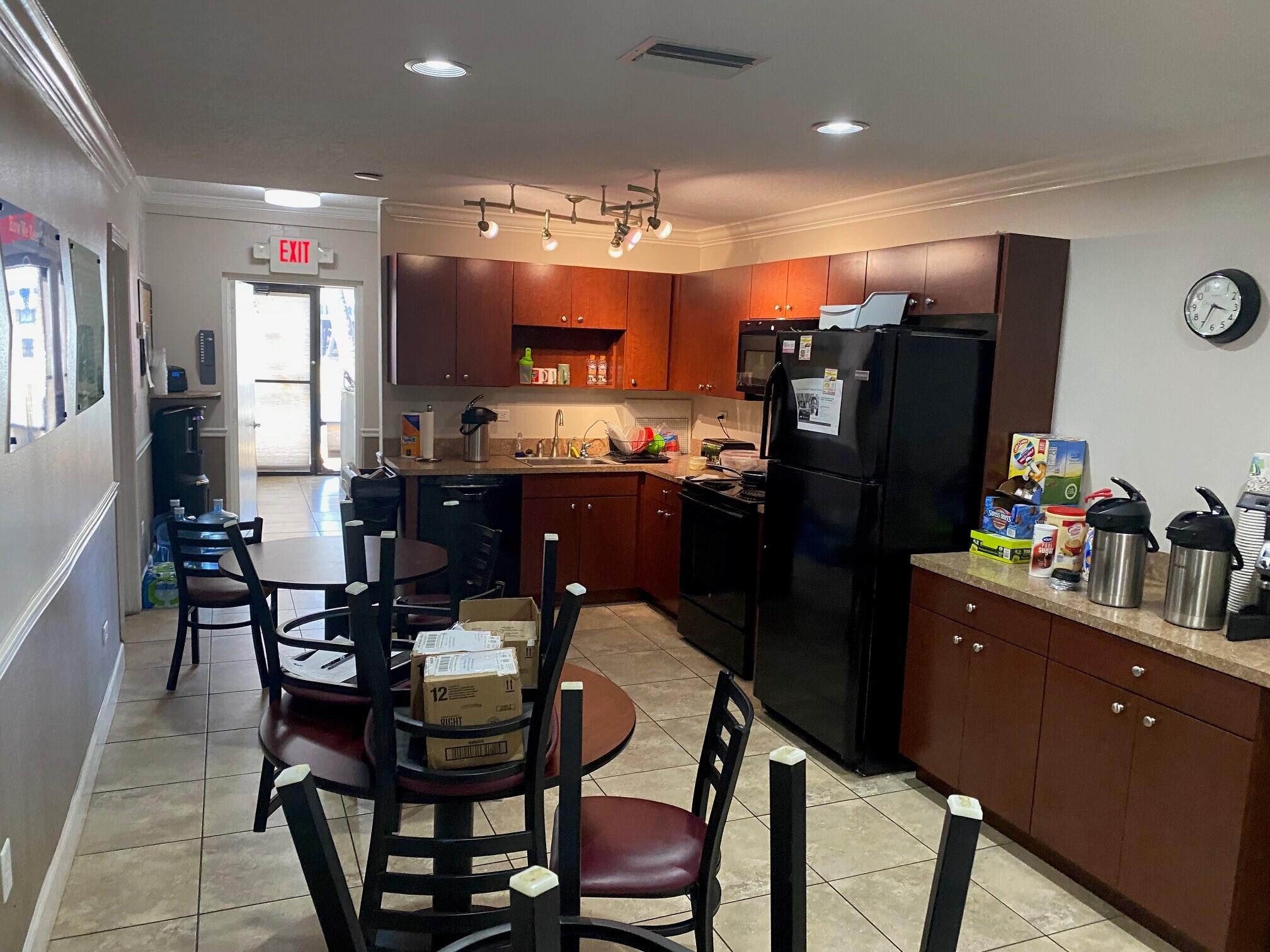 700 South John Rodes Boulevard, Unit B7 & B8 Melbourne, FL 32904 - Photo 9 of 10 a kitchen with a dining table chairs refrigerator and microwave