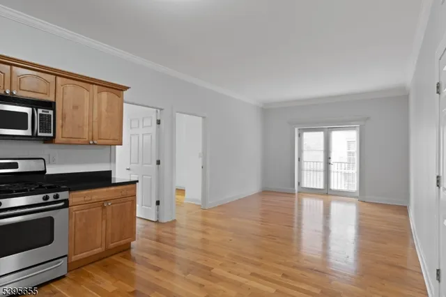 a kitchen with granite countertop a stove a microwave and a hard wood floors
