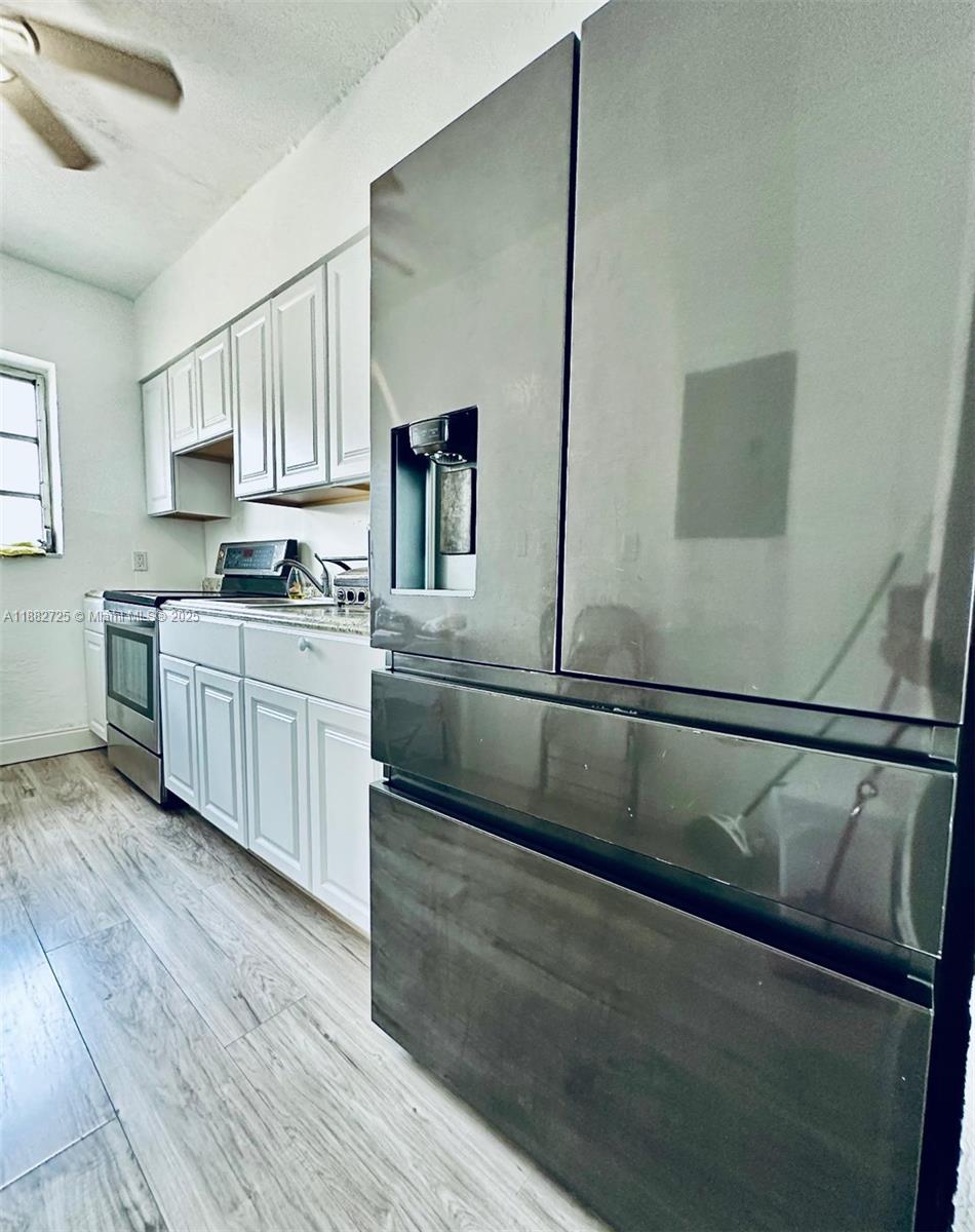 7712 Byron Avenue, Unit 3 Miami Beach, FL 33141 - Photo 5 of 8 a kitchen with stainless steel appliances granite countertop a sink a stove top oven and wooden floors