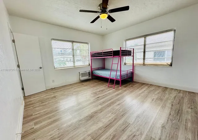 a view of a bedroom with wooden floor and windows