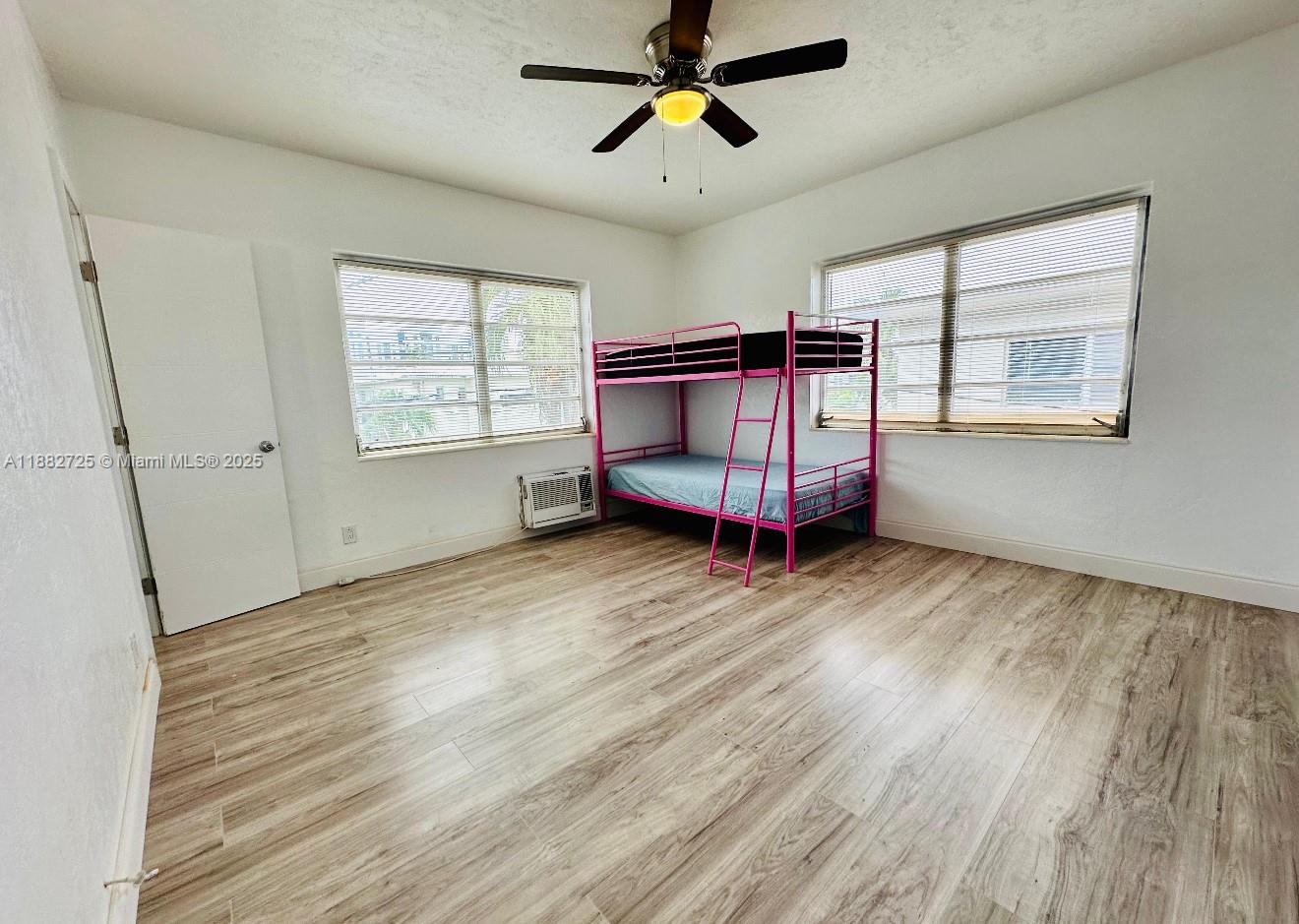 7712 Byron Avenue, Unit 3 Miami Beach, FL 33141 - Photo 6 of 8 a view of a bedroom with wooden floor and windows
