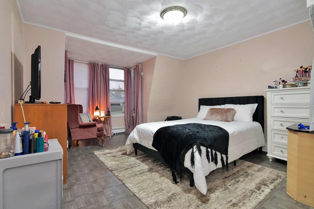 276 Broadway Lawrence, MA 01841 - Photo 17 of 27 a bedroom with a bed table chair and flat screen tv