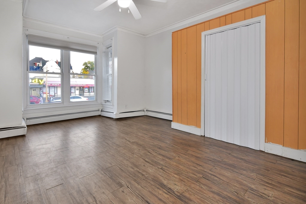 276 Broadway Lawrence, MA 01841 - Photo 7 of 27 an empty room with wooden floor and windows with curtains view