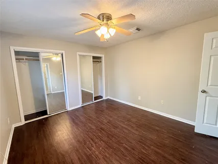 an empty room with wooden floor and a ceiling fan