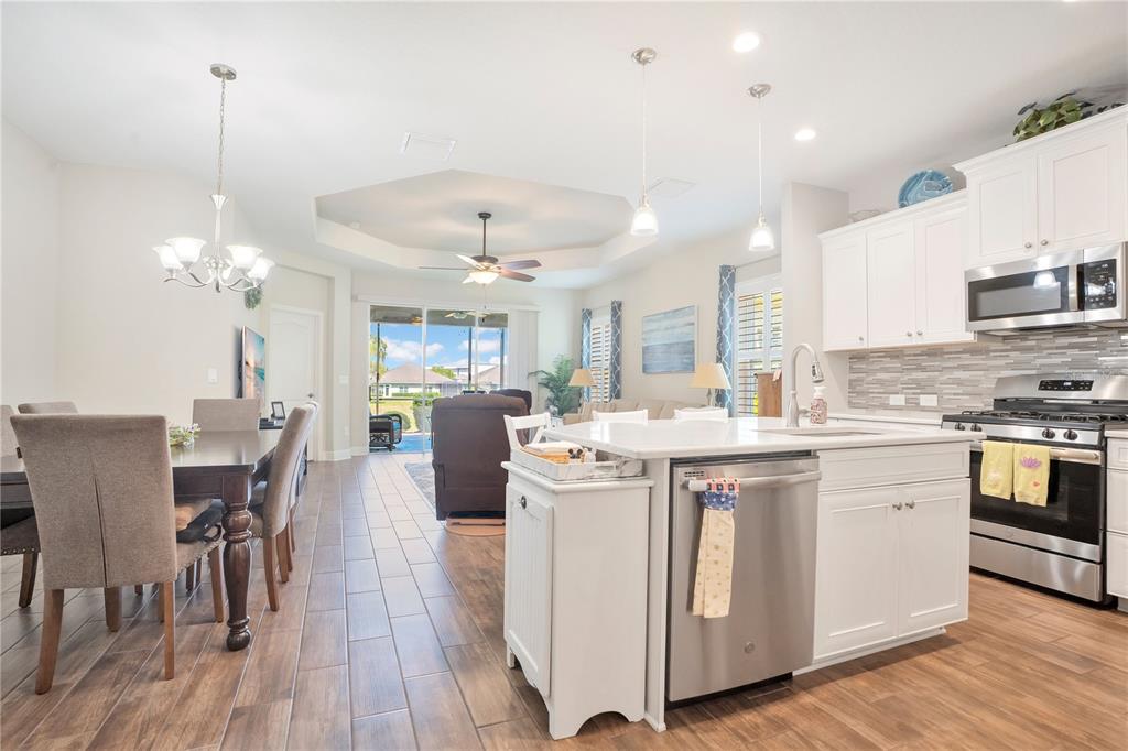 13541 Circa Crossing Drive Lithia, FL 33547 - Photo 17 of 52 a kitchen with stainless steel appliances a white table chairs and a wooden floors
