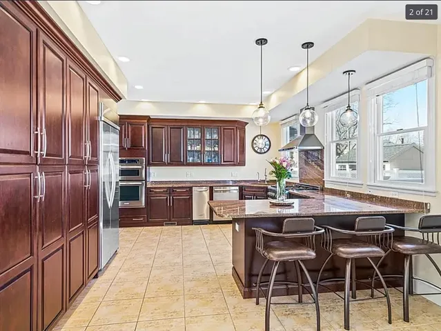 a kitchen with stainless steel appliances kitchen island granite countertop a table chairs in it and wooden floors
