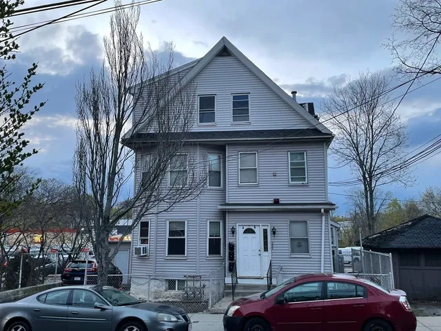 a front view of a house with cars parked
