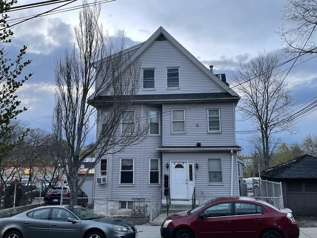 a front view of a house with cars parked