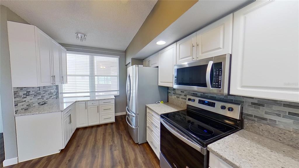 6495 Shoreline Drive, Unit 8104 St. Petersburg, FL 33708 - Photo 25 of 70 a kitchen with stainless steel appliances a stove microwave and cabinets