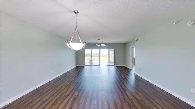 a view of a room with wooden floor ceiling fan and window