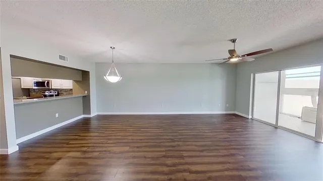 a view of empty room with wooden floor and ceiling fan