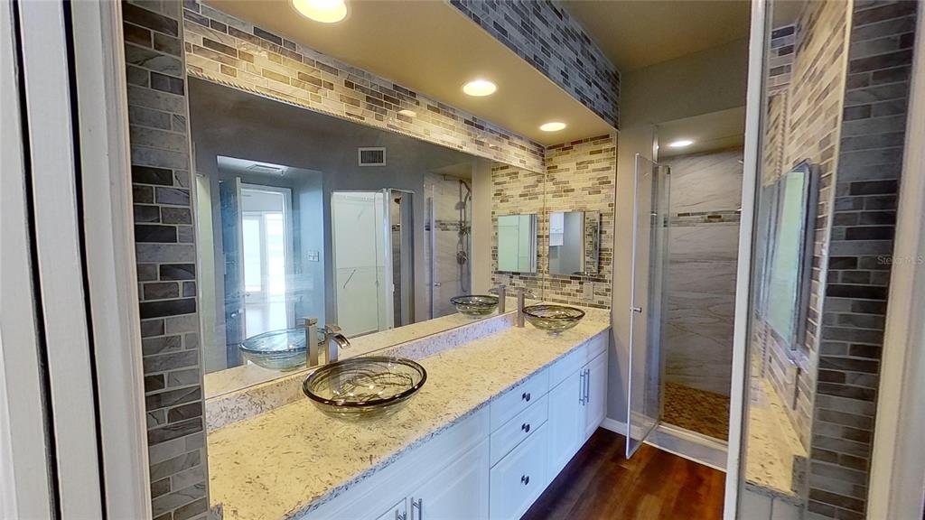 6495 Shoreline Drive, Unit 8104 St. Petersburg, FL 33708 - Photo 41 of 70 a bathroom with a granite countertop sink a mirror and shower