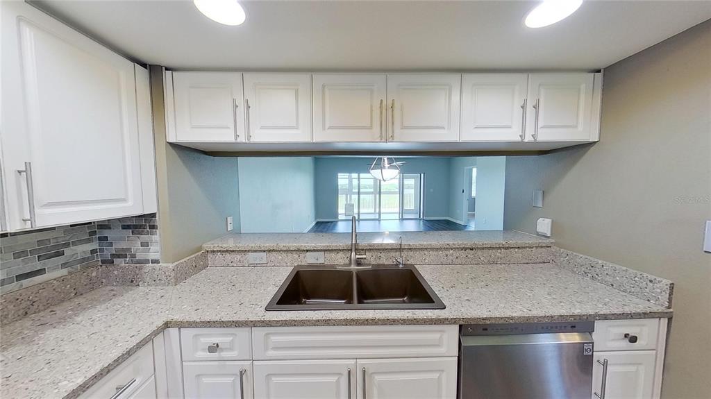 6495 Shoreline Drive, Unit 8104 St. Petersburg, FL 33708 - Photo 6 of 70 a kitchen with granite countertop a sink dishwasher a stove and cabinets with wooden floor