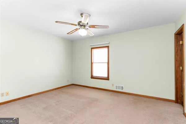 an empty room with windows and fan