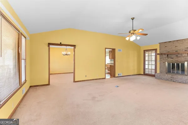 an empty room with windows and chandelier fan