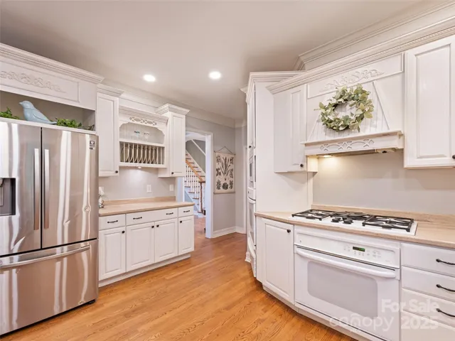 a kitchen with granite countertop a white cabinets and refrigerator with wooden floor