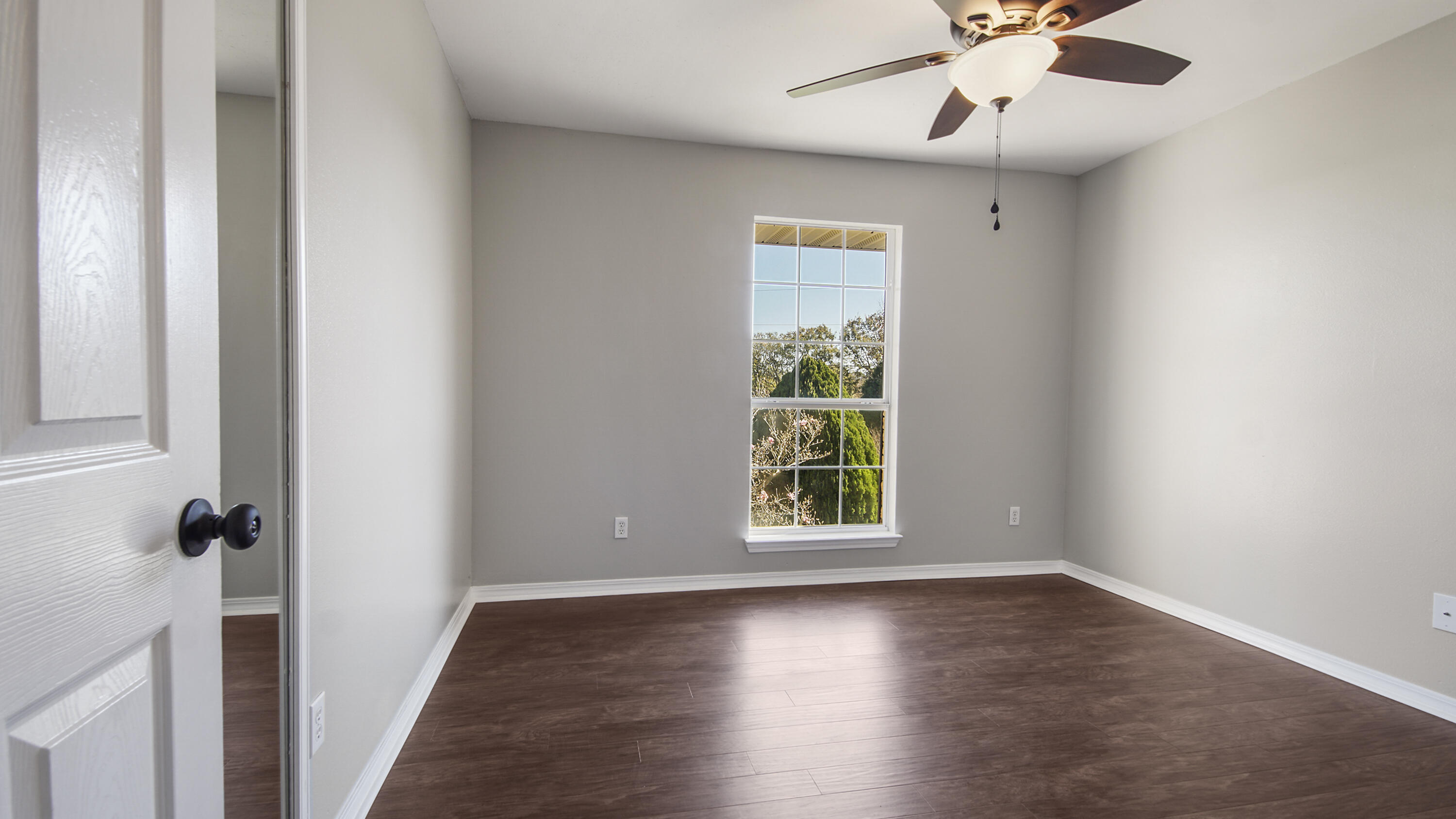 5200 Whitehurst Lane Crestview, FL 32536 - Photo 22 of 49 an empty room with wooden floor chandelier fan and windows
