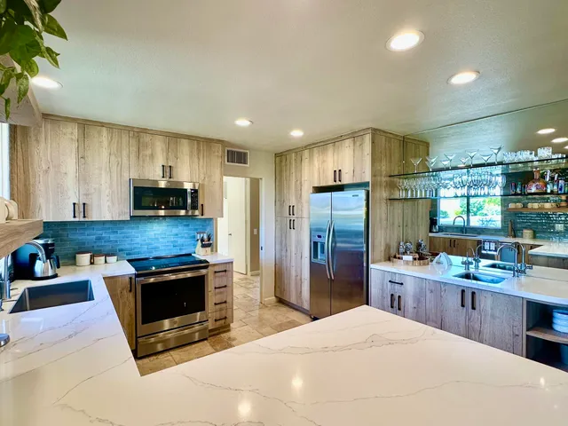 a kitchen with stainless steel appliances a stove a sink a refrigerator cabinets and a counter top space