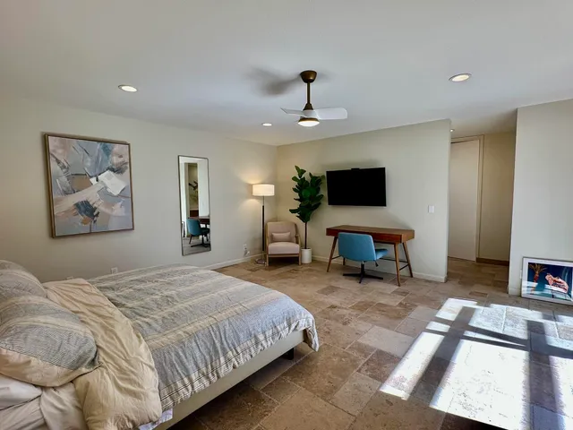 a spacious bedroom with a bed and a flat screen tv