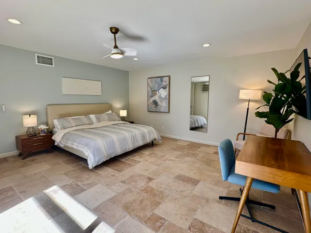 a bedroom with a bed a chair and potted plant on the table