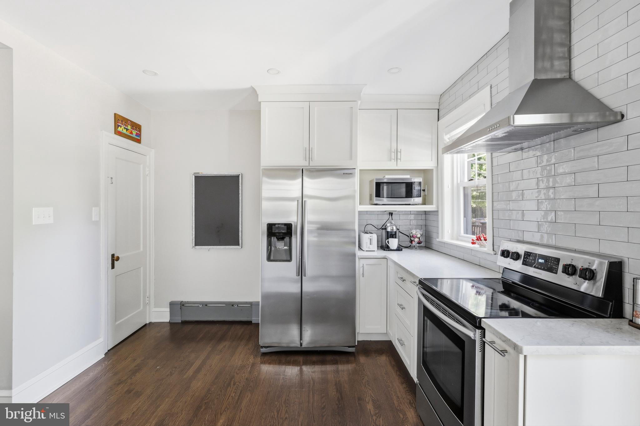 307 East Gravers Lane Philadelphia, PA 19118 - Photo 12 of 44 a kitchen with stainless steel appliances a microwave a stove a sink dishwasher a refrigerator and white cabinets with wooden floor