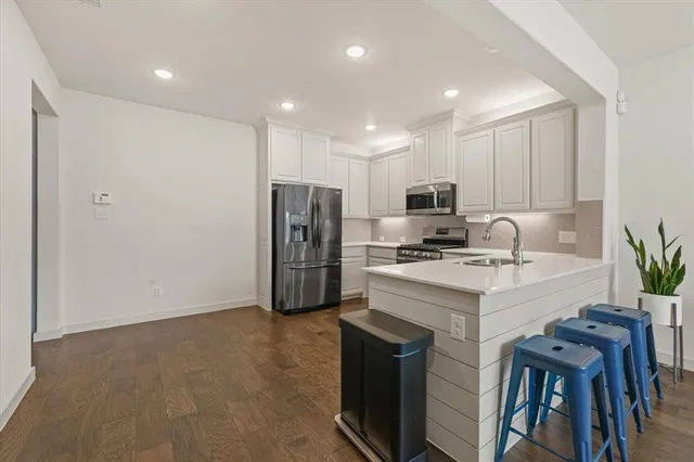 a kitchen with stainless steel appliances a refrigerator sink and white cabinets