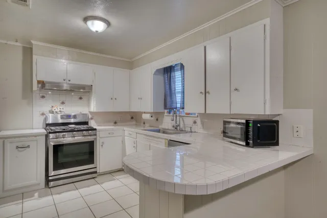 a kitchen with stainless steel appliances granite countertop a sink stove and cabinets