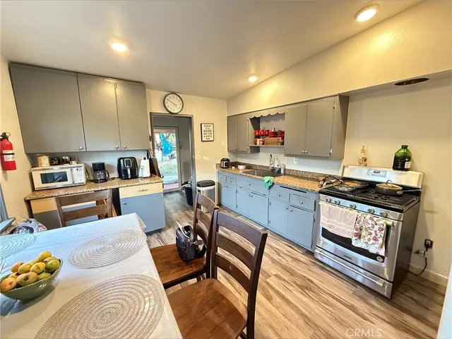 a living room with stainless steel appliances furniture a rug and a kitchen view
