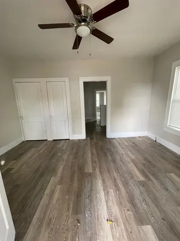 a view of empty room with wooden floor and fan
