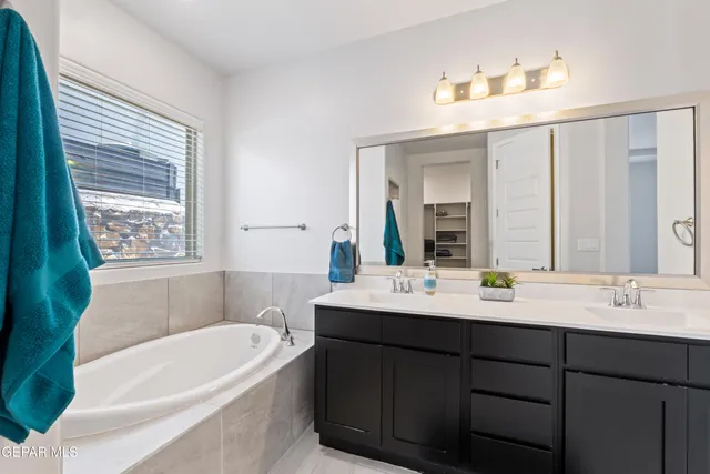 a bathroom with a tub a sink and mirror