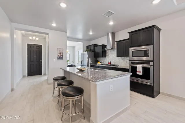 a kitchen with stainless steel appliances kitchen island granite countertop a stove and a refrigerator