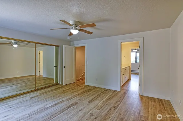 a view of empty room with wooden floor and fan