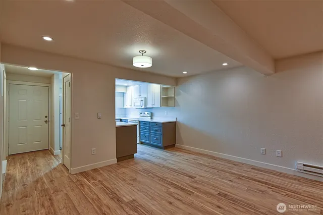 a view of kitchen and empty room with wooden floor