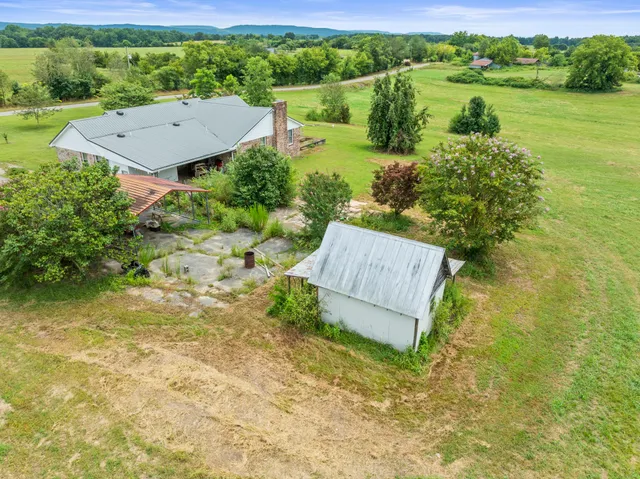 an aerial view of a residential houses with outdoor space and trees all around