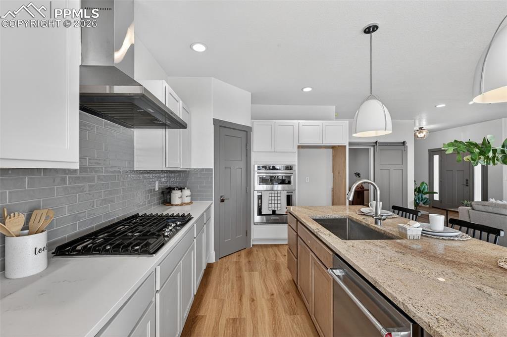 12955 Sunrise Ridge Drive Peyton, CO 80831 - Photo 19 of 49 a kitchen with stainless steel appliances granite countertop a sink a stove and a wooden floors