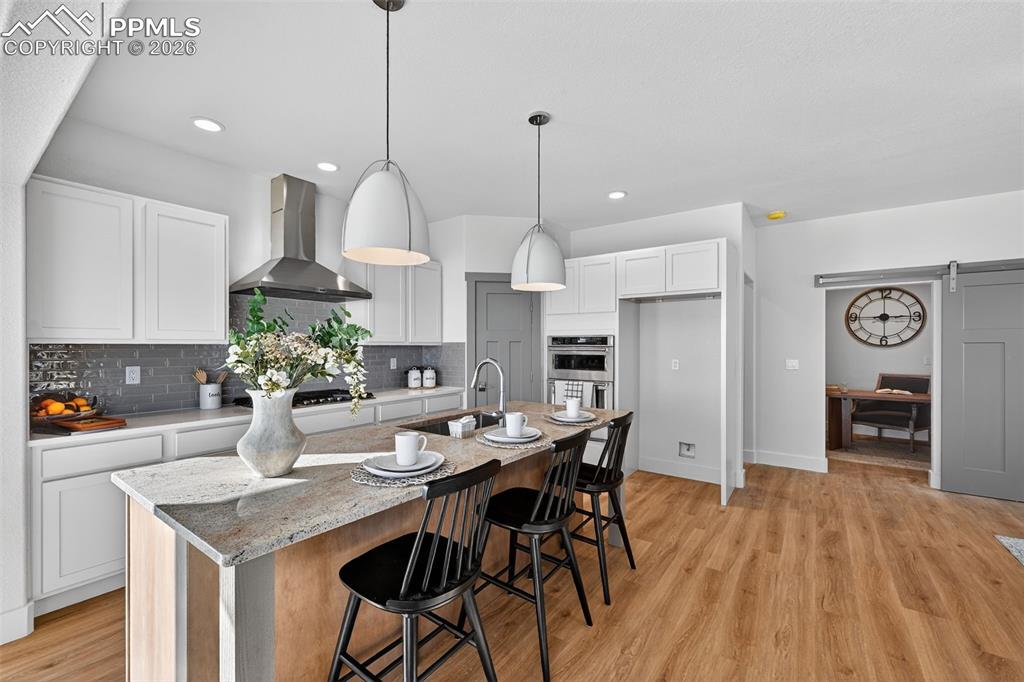 12955 Sunrise Ridge Drive Peyton, CO 80831 - Photo 20 of 49 a kitchen with stainless steel appliances kitchen island granite countertop a dining table chairs and white cabinets