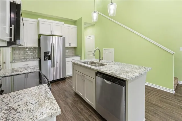 a kitchen with stainless steel appliances kitchen island granite countertop a stove and a wooden floors
