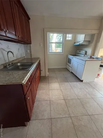 a kitchen with granite countertop a sink a stove and cabinets