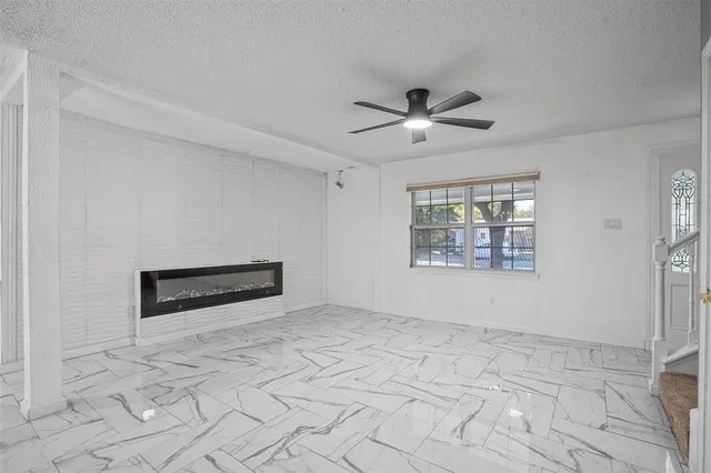 an empty room with windows and ceiling fan