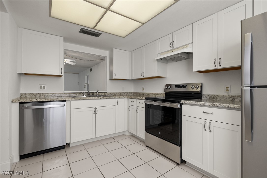 7068 Nantucket Circle, Unit 3 North Fort Myers, FL 33917 - Photo 6 of 17 a kitchen with granite countertop white cabinets and appliances