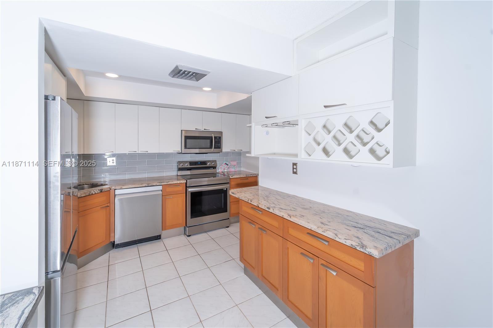 100 Golden Isles Drive, Unit 809 Hallandale Beach, FL 33009 - Photo 5 of 18 a kitchen with stainless steel appliances granite countertop a stove top oven a sink and a refrigerator