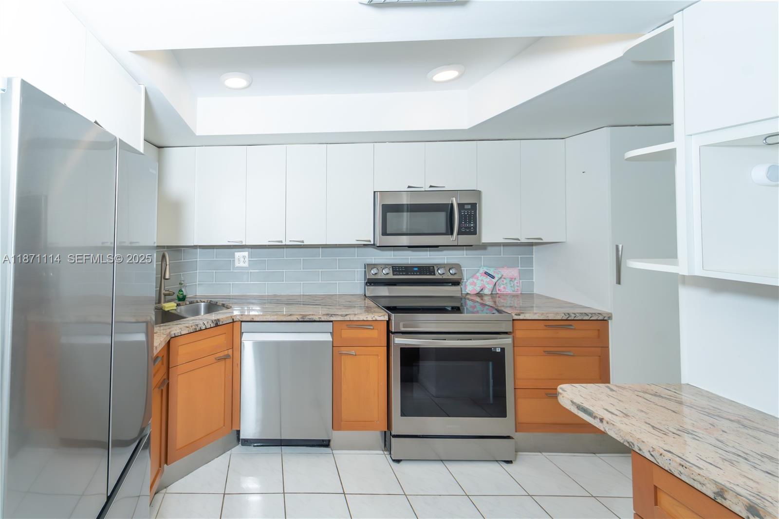 100 Golden Isles Drive, Unit 809 Hallandale Beach, FL 33009 - Photo 6 of 18 a kitchen with stainless steel appliances granite countertop a stove a sink and a microwave