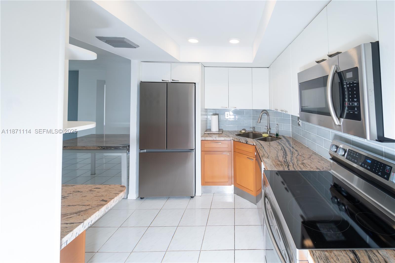 100 Golden Isles Drive, Unit 809 Hallandale Beach, FL 33009 - Photo 7 of 18 a kitchen with stainless steel appliances granite countertop a refrigerator and a stove