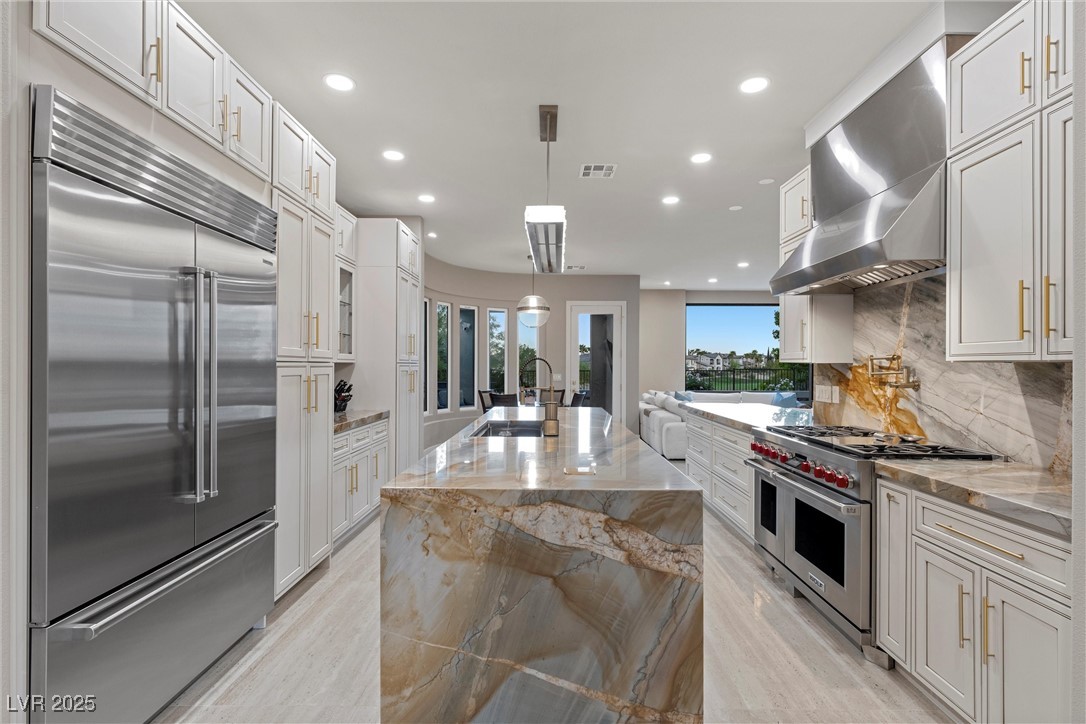 1911 Alcova Ridge Drive Las Vegas, NV 89135 - Photo 12 of 43 Kitchen with wall chimney range hood, premium appliances, a sink, and white cabinets